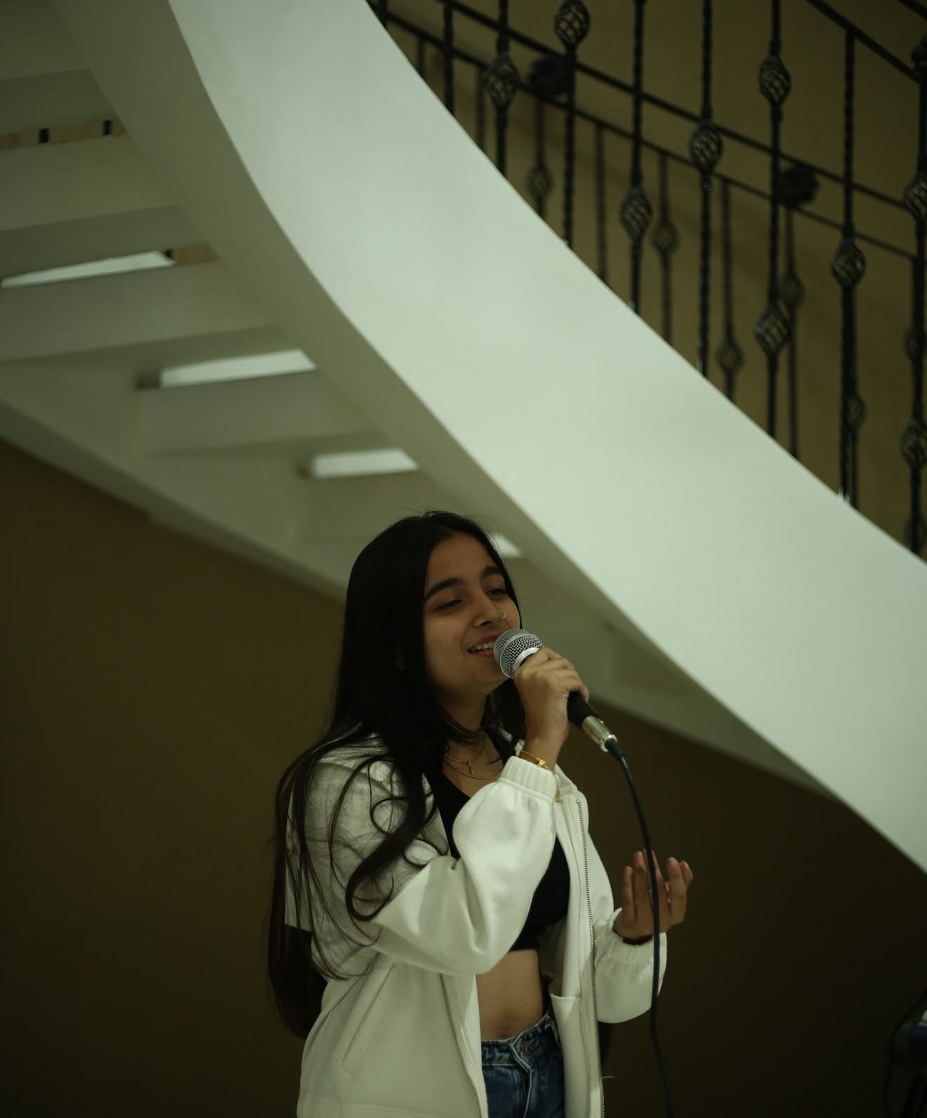 A singer performing solo beneath a spiral staircase