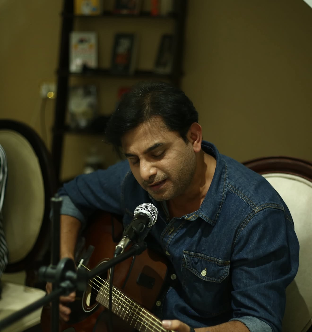 A musician singing closely into a microphone while playing guitar