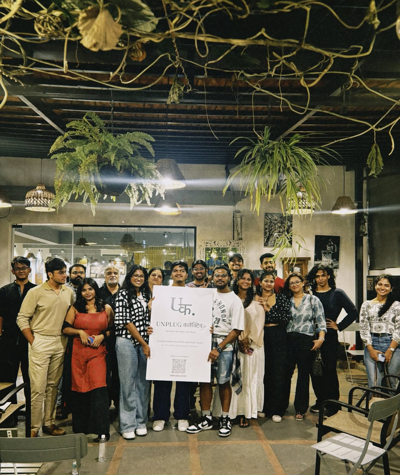 The Unplug Collective community gathered together, holding a sign with the collective's mark